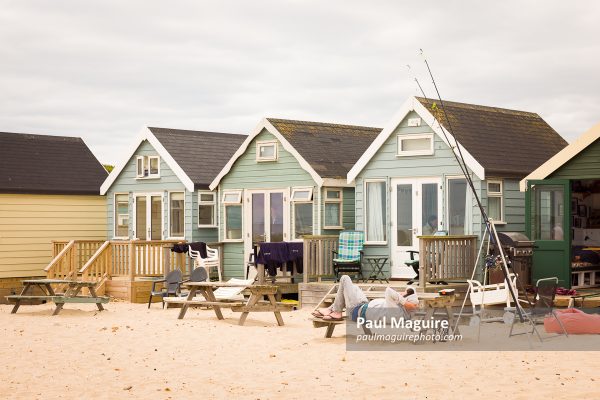 Man relaxing outside a beach hut, Hengistbury Head, Dorset, UK