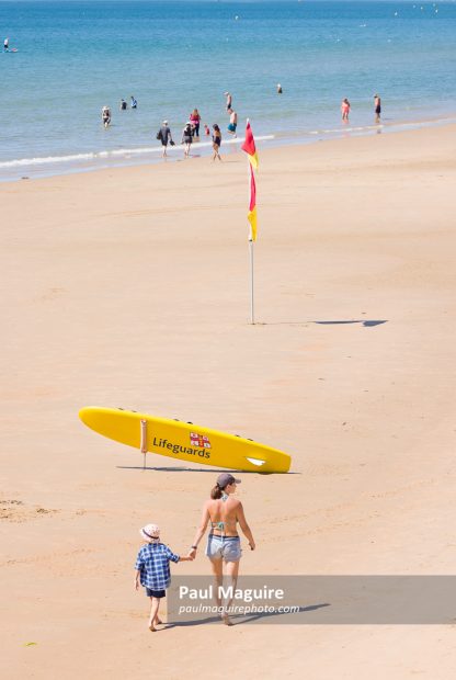 Woman and child on Bournemouth beach, RNLI lifeguard surfboard