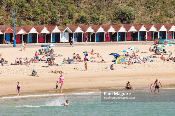 People and beach huts on Bournemouth beach, Dorset, UK