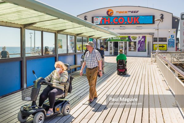 Elderly couple with woman on mobility scooter, Bournemouth Pier
