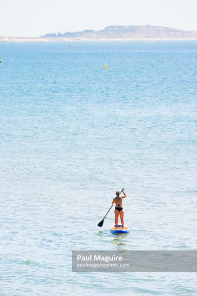 Mature woman paddle boarding, Bournemouth, UK