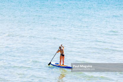 Mature woman paddle boarding, Bournemouth, UK