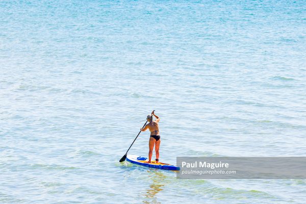 Mature woman paddle boarding, Bournemouth, UK