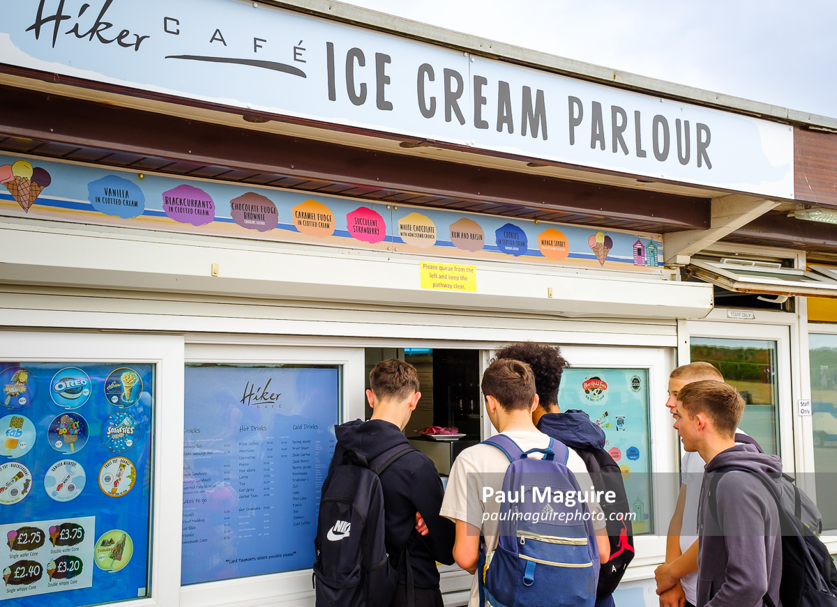 Boys buying icecream at ice cream shop on Dorset coast, UK