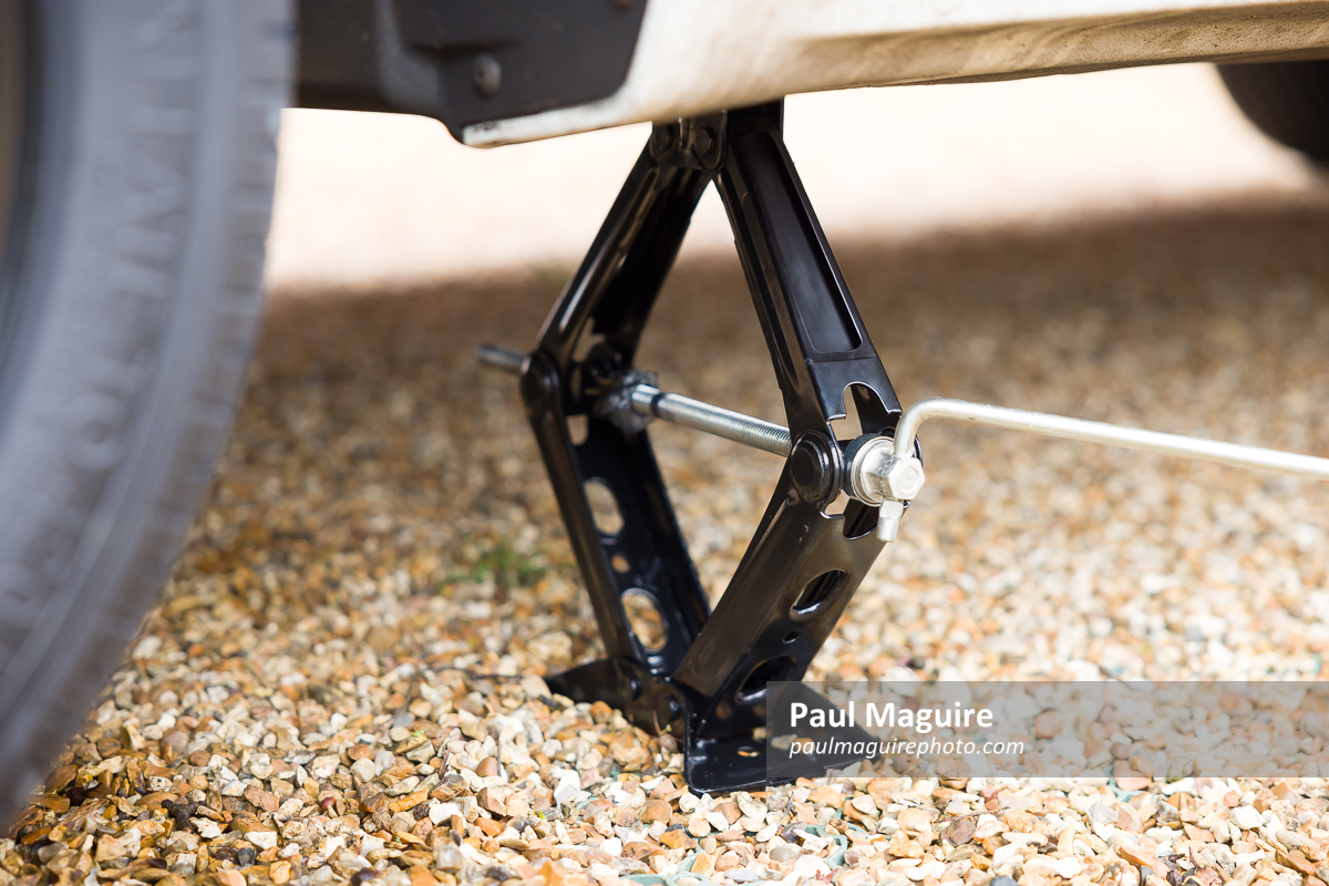 Close up of a car jack underneath a car